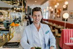 A man in a light blue blazer and white shirt at a restaurant bar