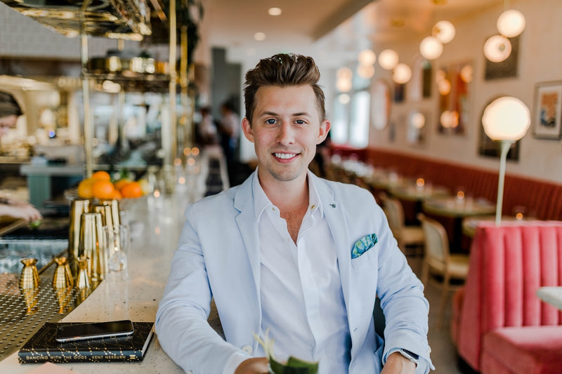 A man in a light blue blazer and white shirt at a restaurant bar