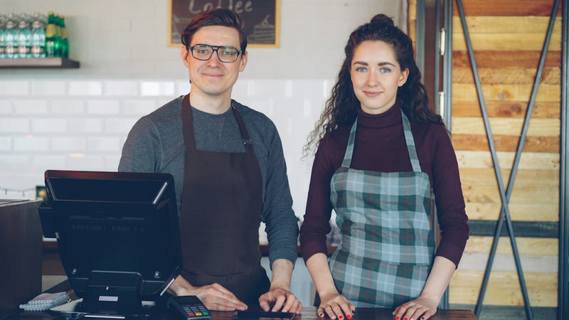 Two baristas are ready for service at their coffee shop