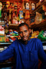 Man in blue shirt standing in a small shop.