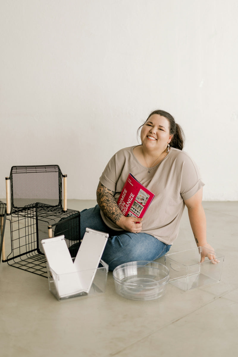 Smiling woman on floor with storage items and a book