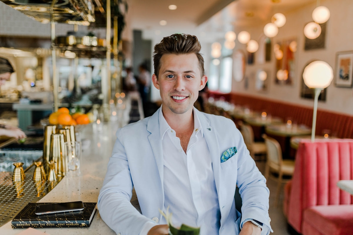 A man in a light blue blazer and white shirt at a restaurant bar