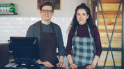 Two baristas are ready for service at their coffee shop