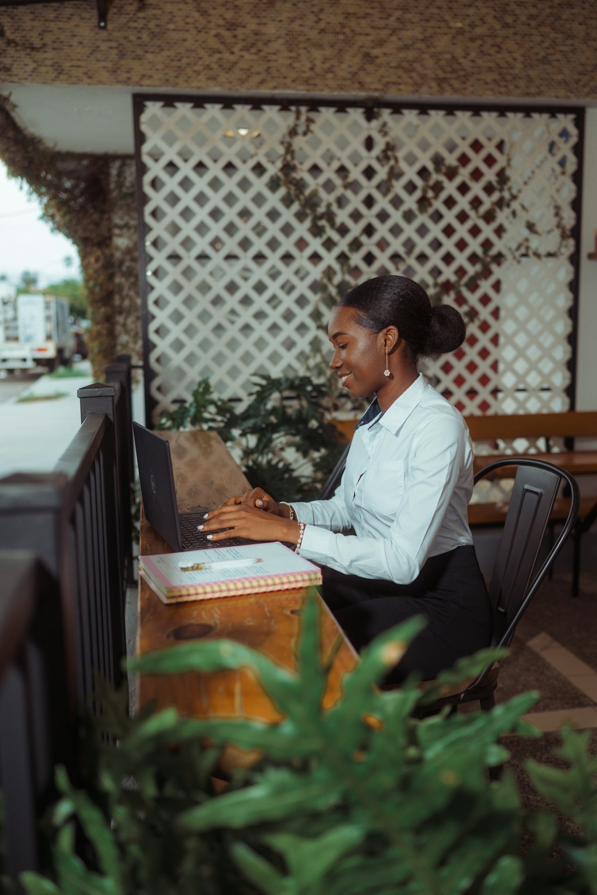 A woman smiling while working on a laptop outdoors
