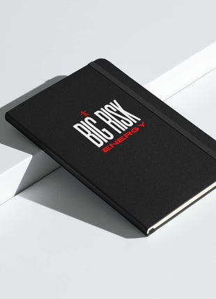 Big Risk Energy Notebook on a white surface, featuring a bold black cover and red lettering for visionary ideas.