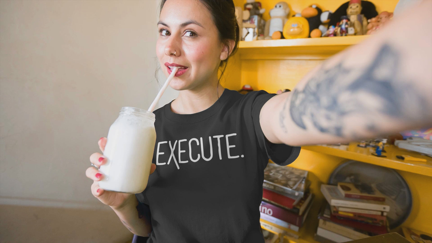 Woman sipping a milkshake in a black EXECUTE T-Shirt, representing entrepreneur apparel and action-oriented mindset.
