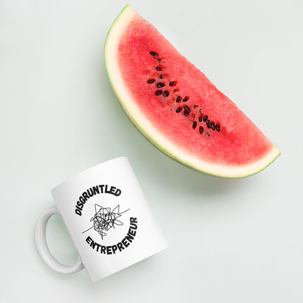Disgruntled Entrepreneur Motivational Coffee Mug next to a slice of watermelon on a white background.